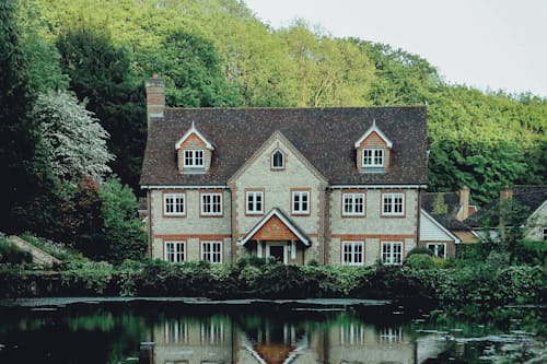 A traditional stone country home by a small pond.